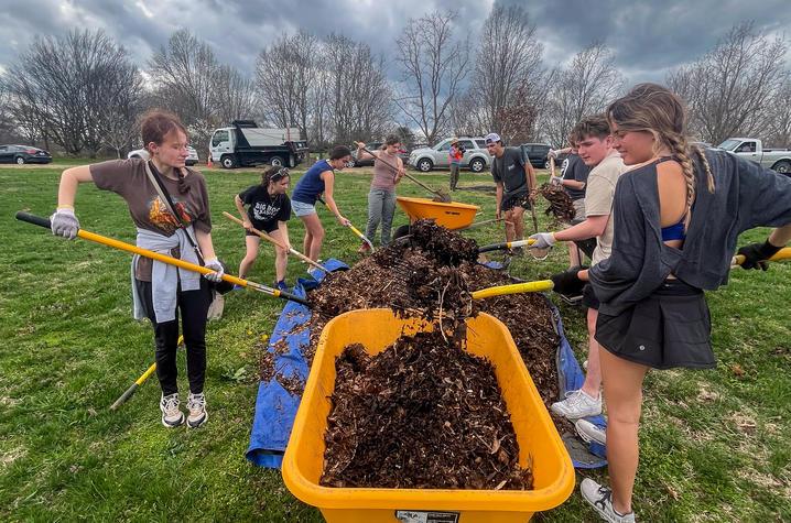students shovel dirt